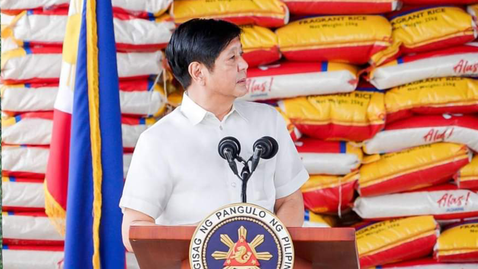 President Marcos Jr. in front of rice bags during a speech in San Jose, Dinagat Islands